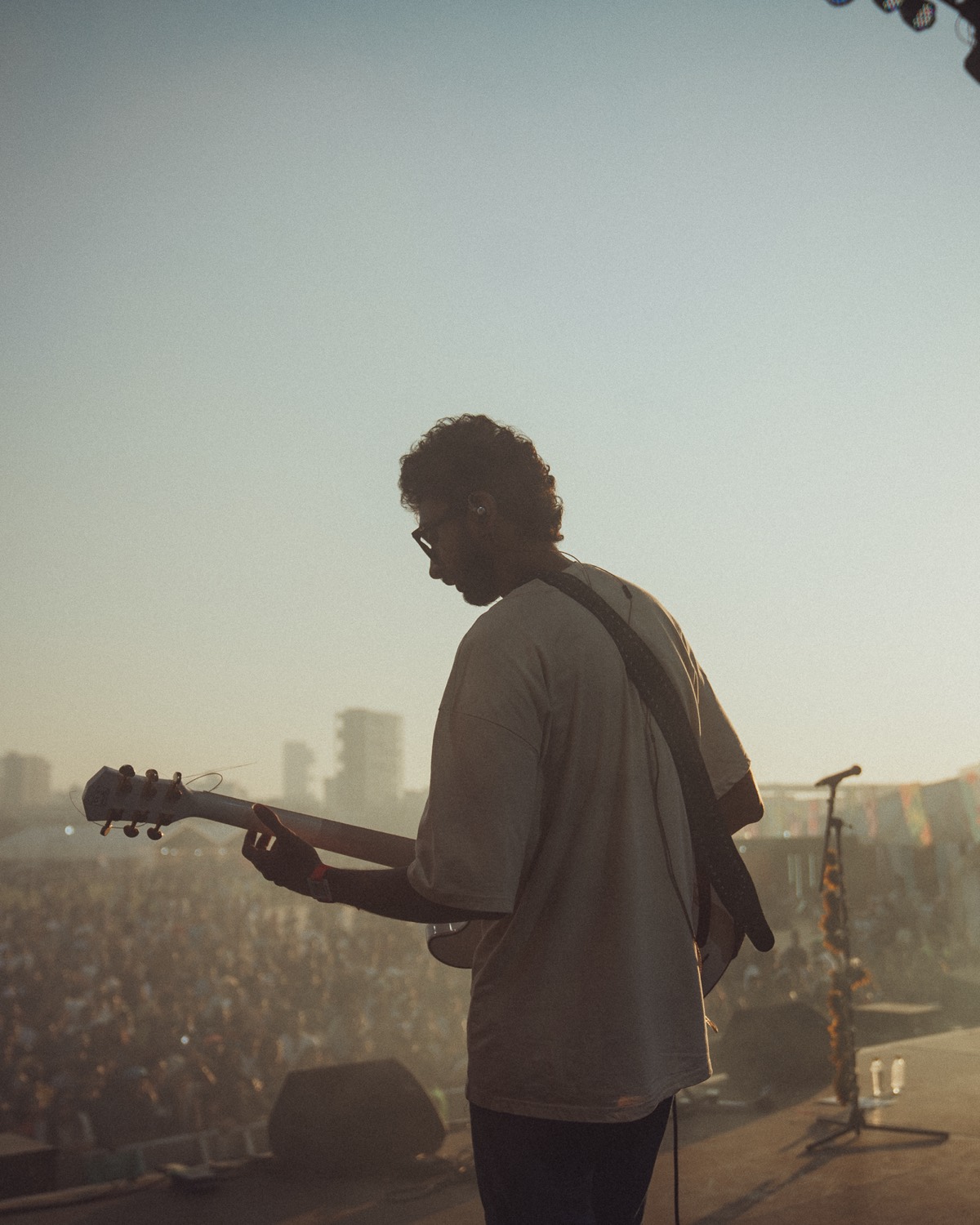 Strangeloop playing guitar on a festival stage in front of a large crowd