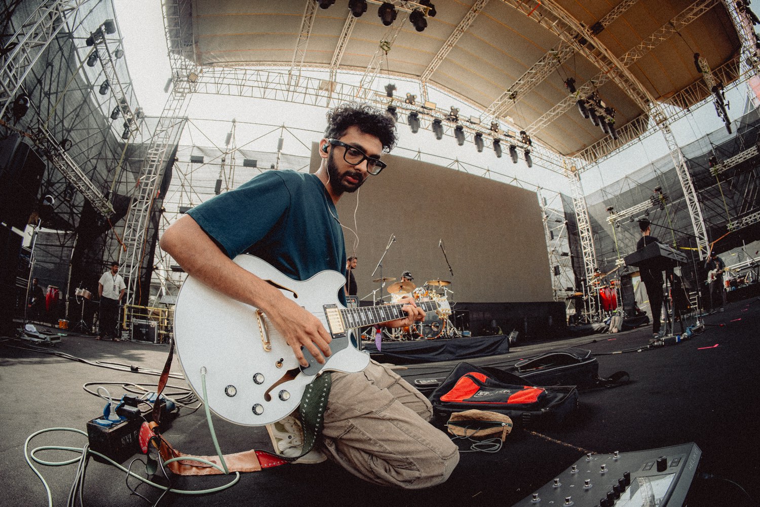 Strangeloop kneeling on a festival stage with his guitar before a show